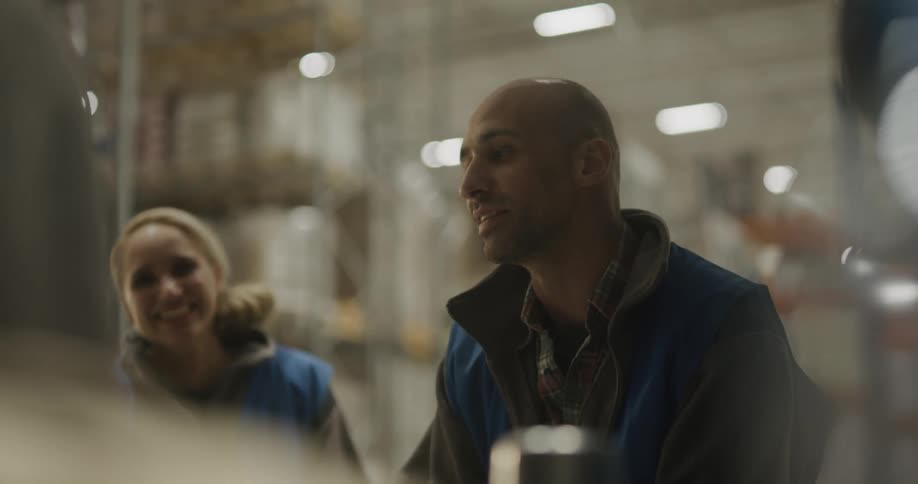 A group of workers standing around talking in a warehouse