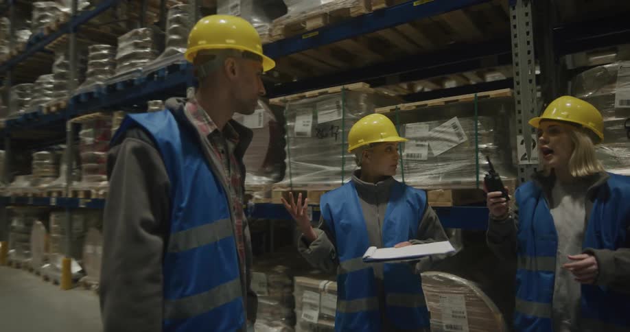 A group of three warehouse workers talking