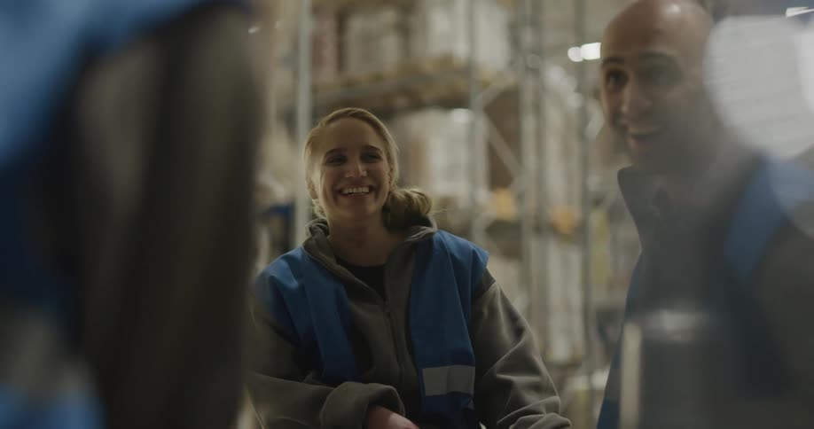 Group of coworkers talking and laughing at break time in the warehouse