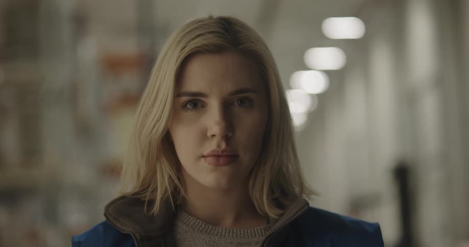 Female employee on a warehouse looks up to the camera