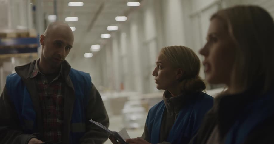 Warehouse workers review paperwork during discussion