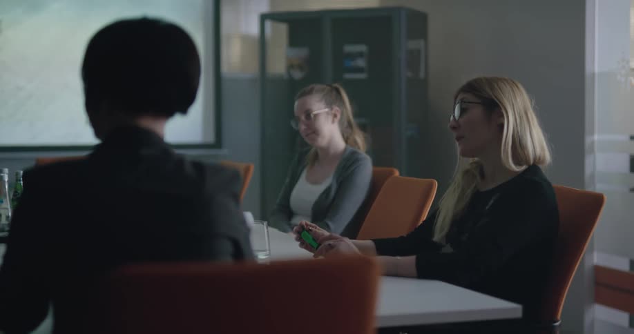 Group of people talking and laughing on a meeting in an office with a bit display on the wall