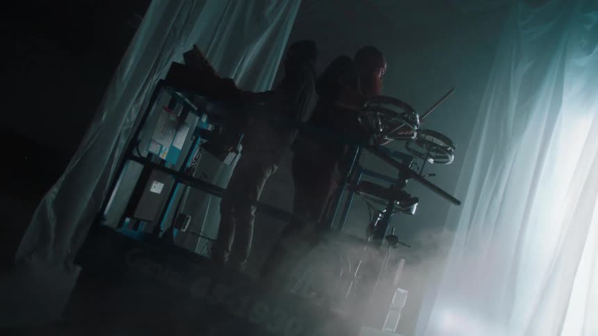 Two men standing on a stage hydraulic lift playing a set of drums and an electric piano keyboard on a stage