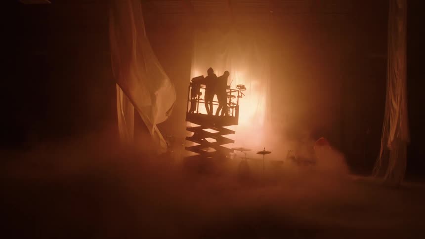 Musicians on a stage play instruments as they are raised on a platform
