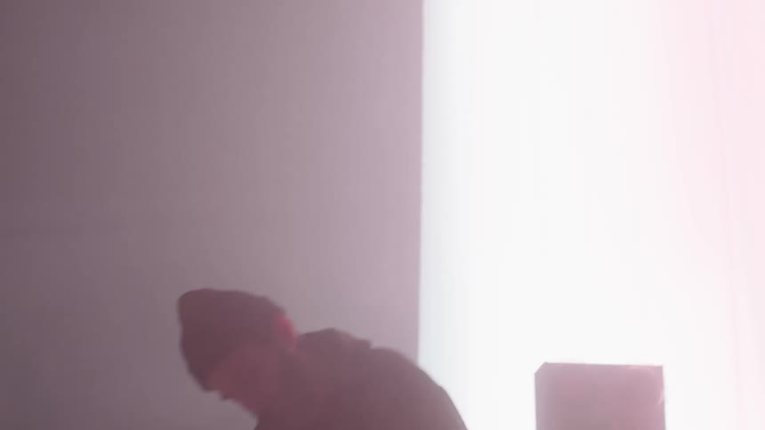 Man plays keyboards under flashing and red tinted lights on stage