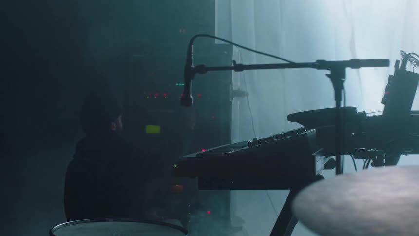Two musician in front of their instrumets on a foggy stage under strobing lights