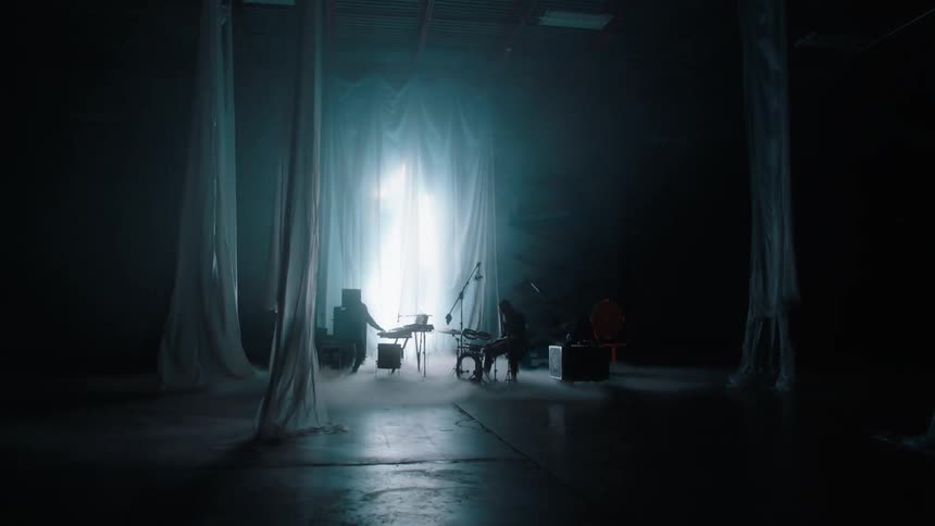 The silhouette of musicians and musical instruments surrounded by columns of fabric on a dramatic film set