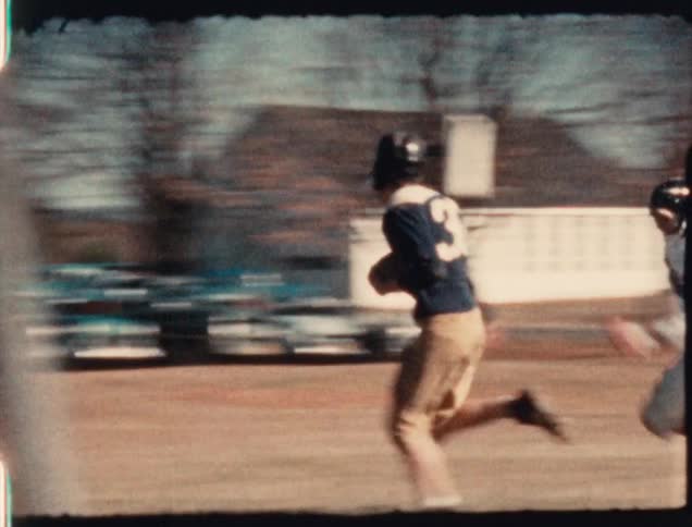 A high school football player is tackled during a 1950's football game