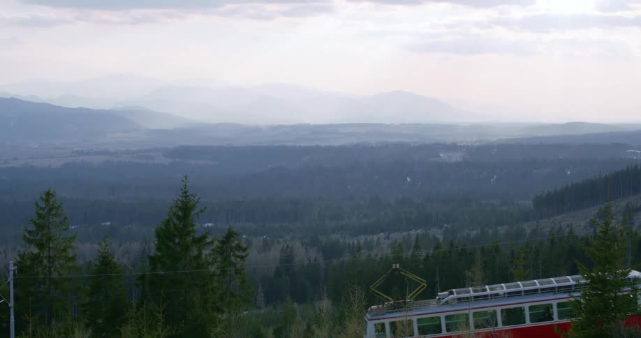 An electric tram runs along the side of a mountain