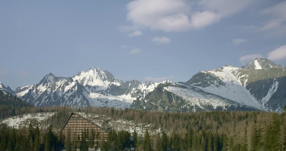 A snow covered mountain and forest with a house nearby