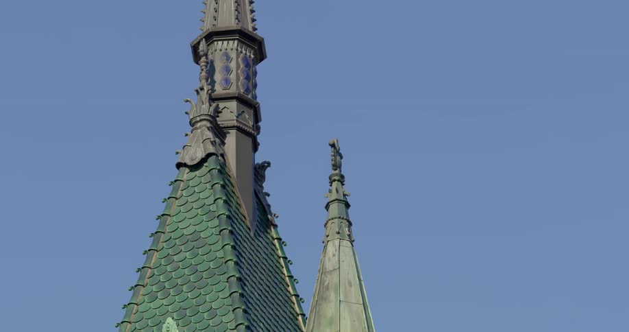 The very top of a building with elaborate architecture has multiple spires that protrude high into the sky