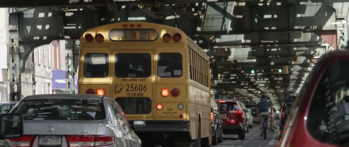 A school bus in traffic moves slowly over a bridge