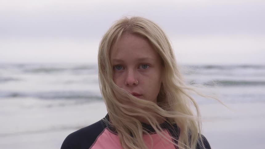 A child is standing outdoors at the beach