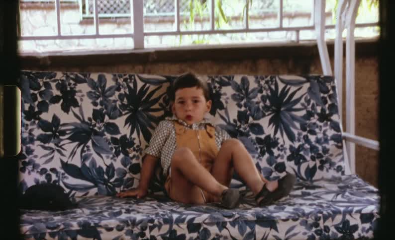 A boy swings on the futon outside