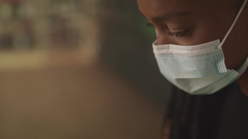 Young woman wearing a surgical face mask inside a dimly lit room