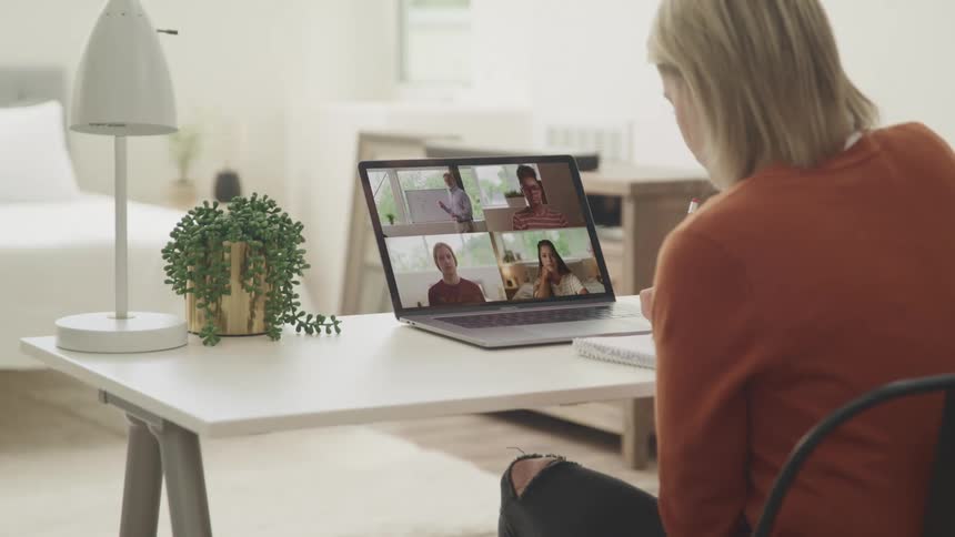 A woman talking to other people on her laptop