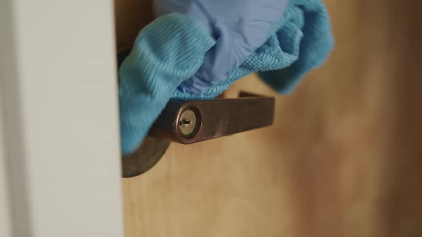 A person is wearing a glove and cleaning a door