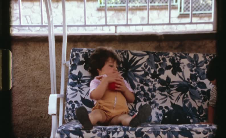 A sister and brother are sitting on a chair outdoors together