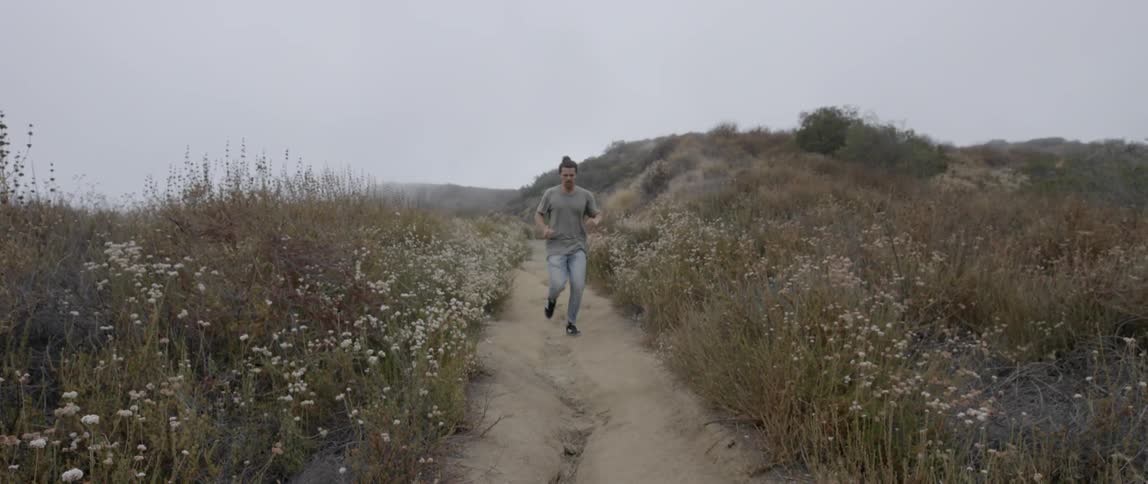 A man runs down a dirt path lined during the day