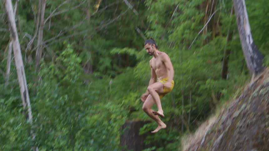 A man jumps off the cliff falling into the water
