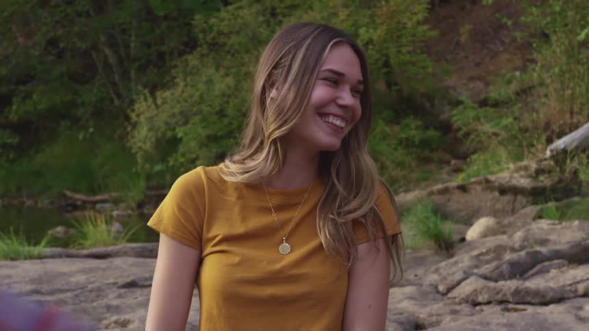 A woman laughing and smiling with flirting with a man outside