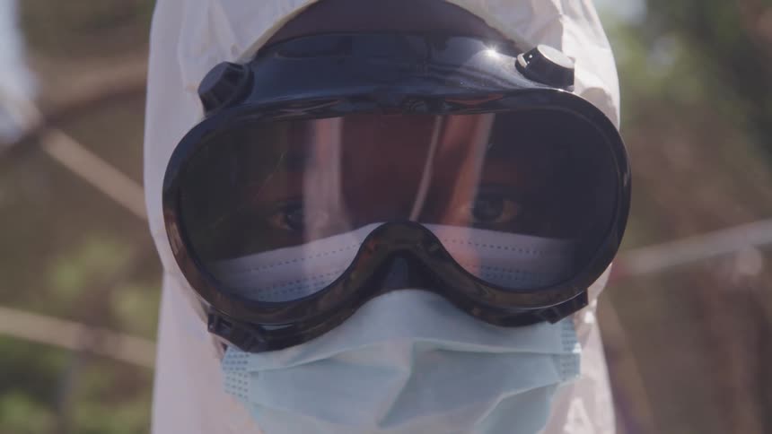 A person standing outside wearing a head covering and goggles looking forward