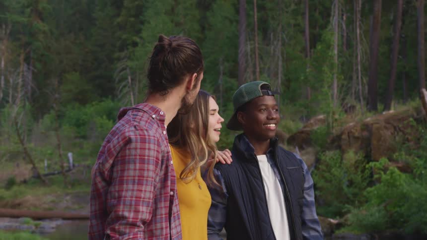 A group of friends standing in the forest talking and smiling