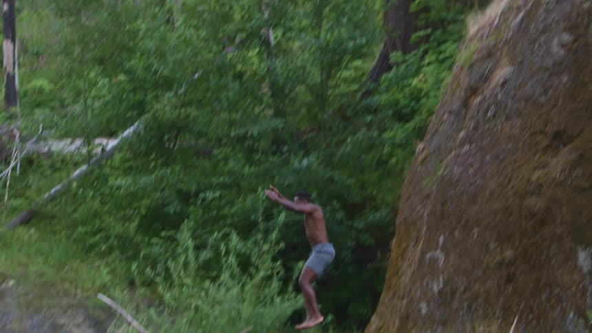 Shirtless muscular young man jumping on a lake in the forest
