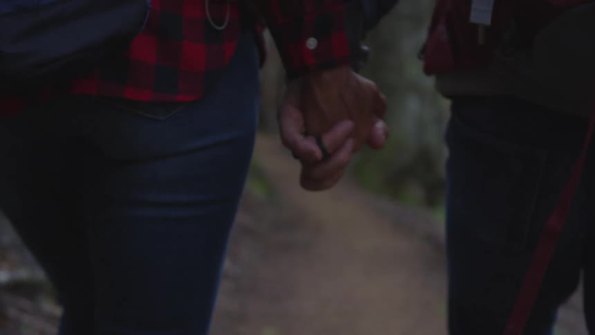Two people are walking outdoors and holding hands