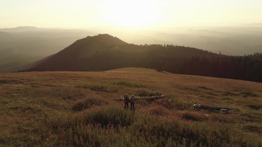 Two people are standing outdoors at dusk