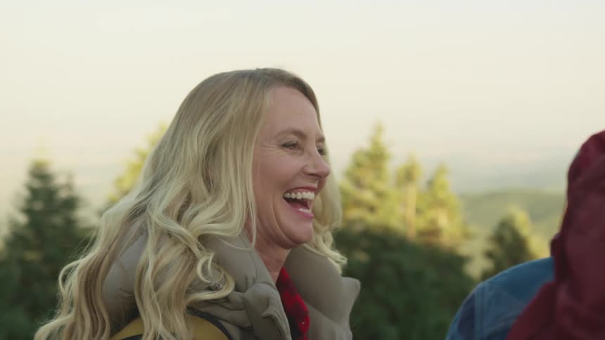 A woman laughs with her husband as they rest during a hike in the woods