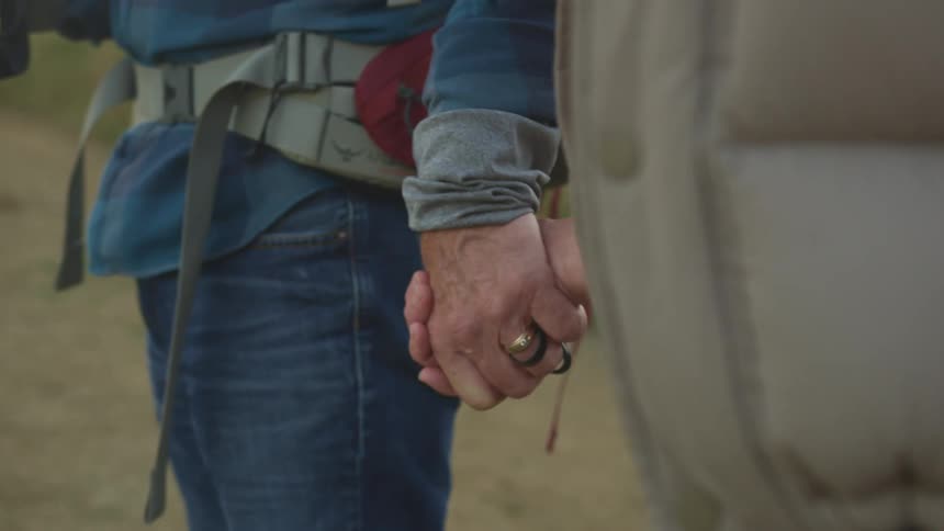 Two people are holding hands and hiking outdoors