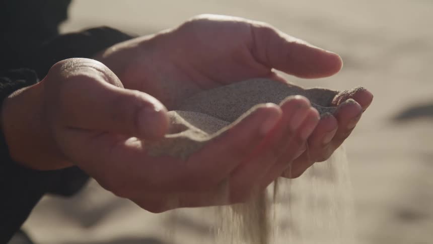 A person holding sand in their hands