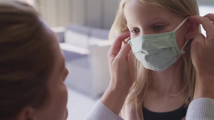 A woman putting on a mask on a girl