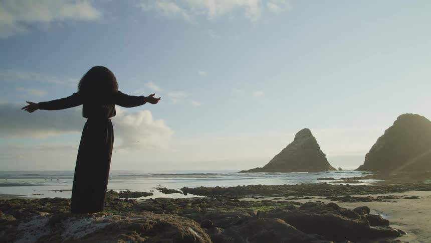 A woman is standing outdoors at the beach