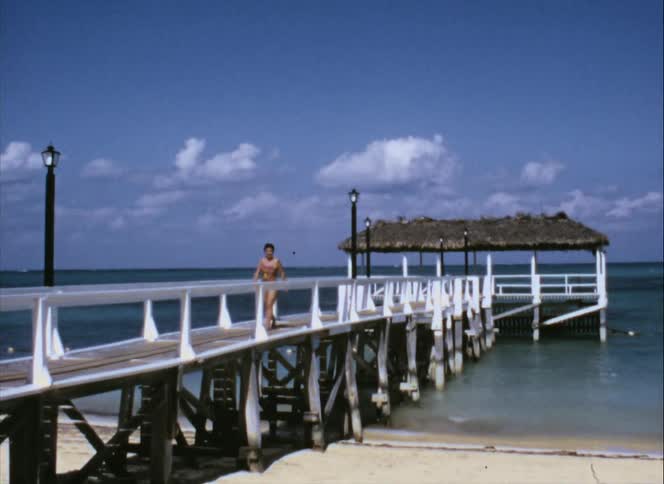 A woman walking on a pier at the beach