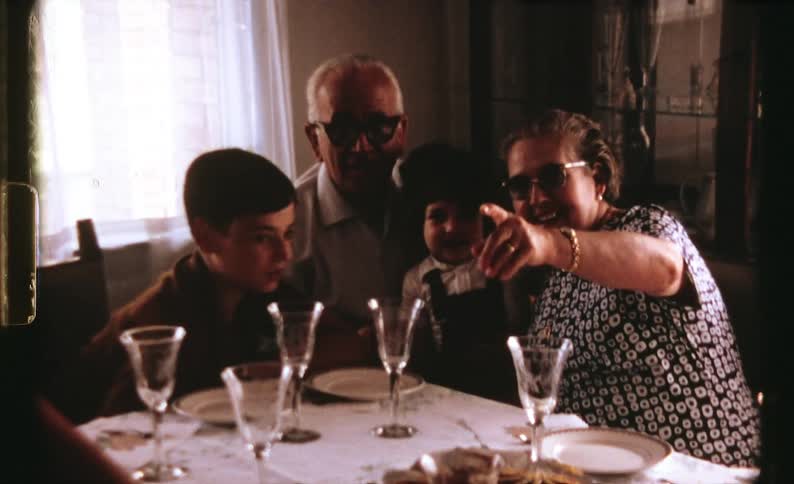 A man a woman a boy and a girl sitting at a table with plates and glasses