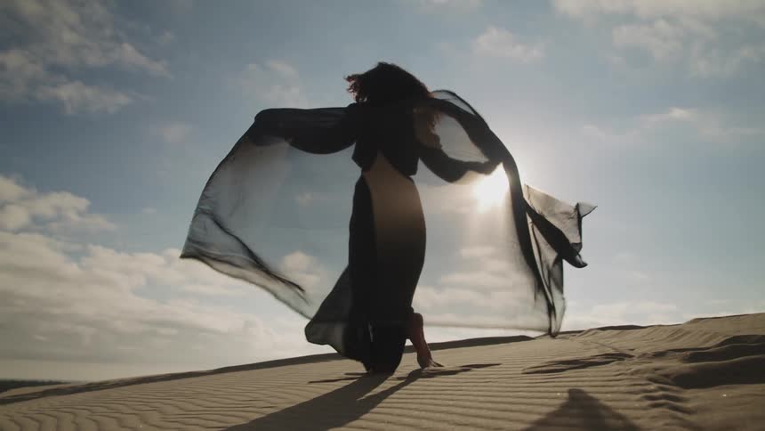 A woman is walking on a sand dune