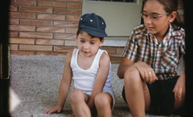 A female playing outside with two children one child is bike riding