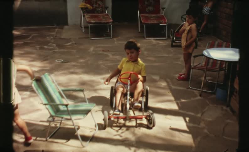 A child rides their cart in the yard