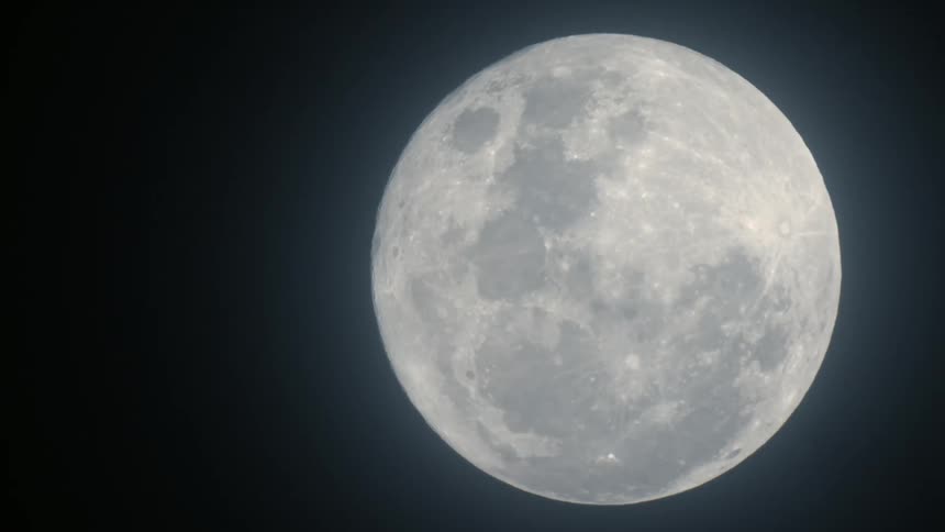 Clouds pass over full moon shining at night