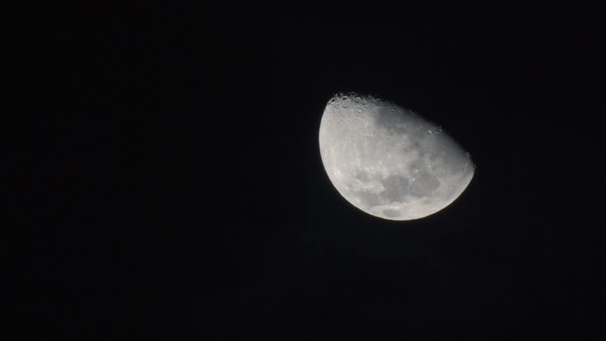 Less than full moon glows against black sky