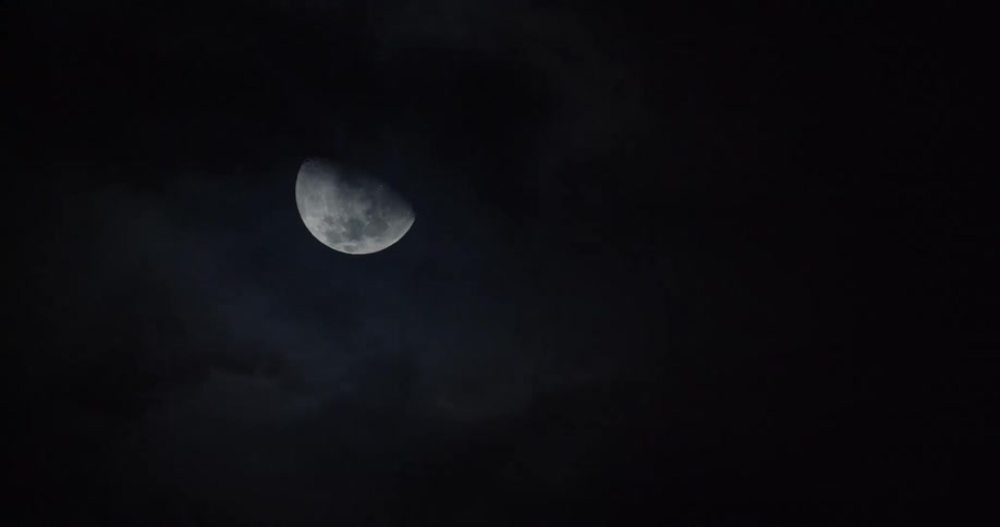 The moon in the night sky with clouds moving in front of it