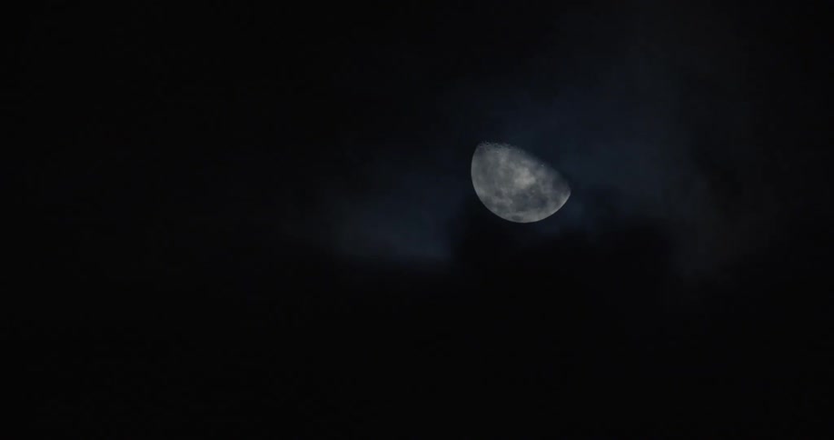 Dark clouds move slowly past the bright moon