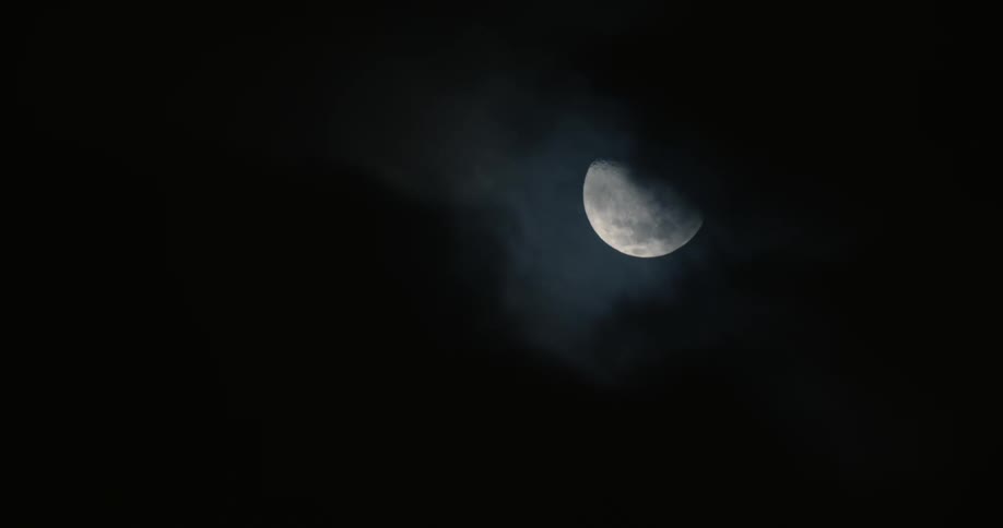 Dark clouds passing before the moon at night