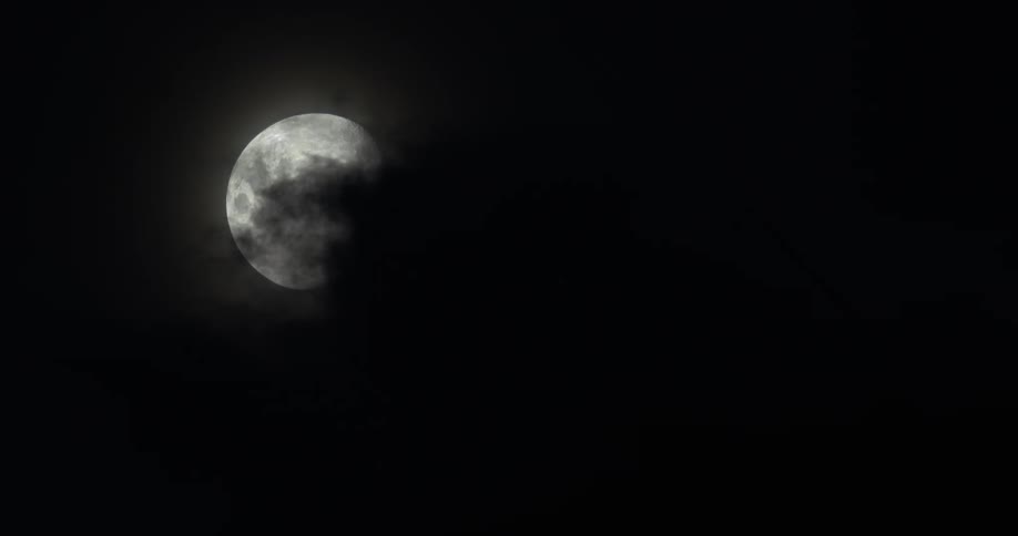 Clouds passing over the moon at night