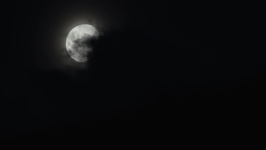 An almost full moon peaking through clouds