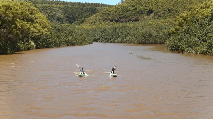 Two people row canoes on a river