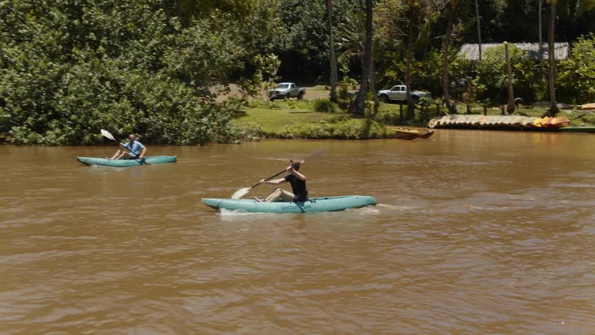 Two men are kayaking on muddy river on sunny day