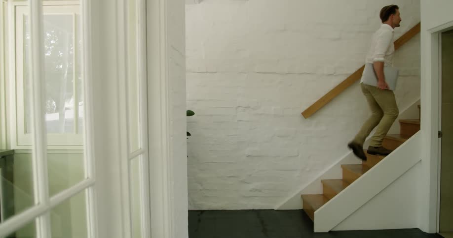 Man carrying a laptop climbs the stairs inside a building